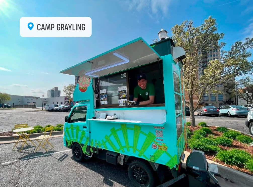 The baby-blue Cookin’ with Beans food truck with Tommy smiling from the serving window